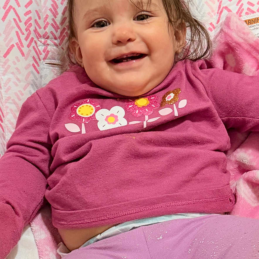 Tatum joined the competition — help win amazing prizes! baby, child, smiling, pink_clothing, sitting, indoor, blanket, baby_seat, happy, face, long_hair, floor, cabinet, home, toddler, cute, portrait, infant, patterned, cozy