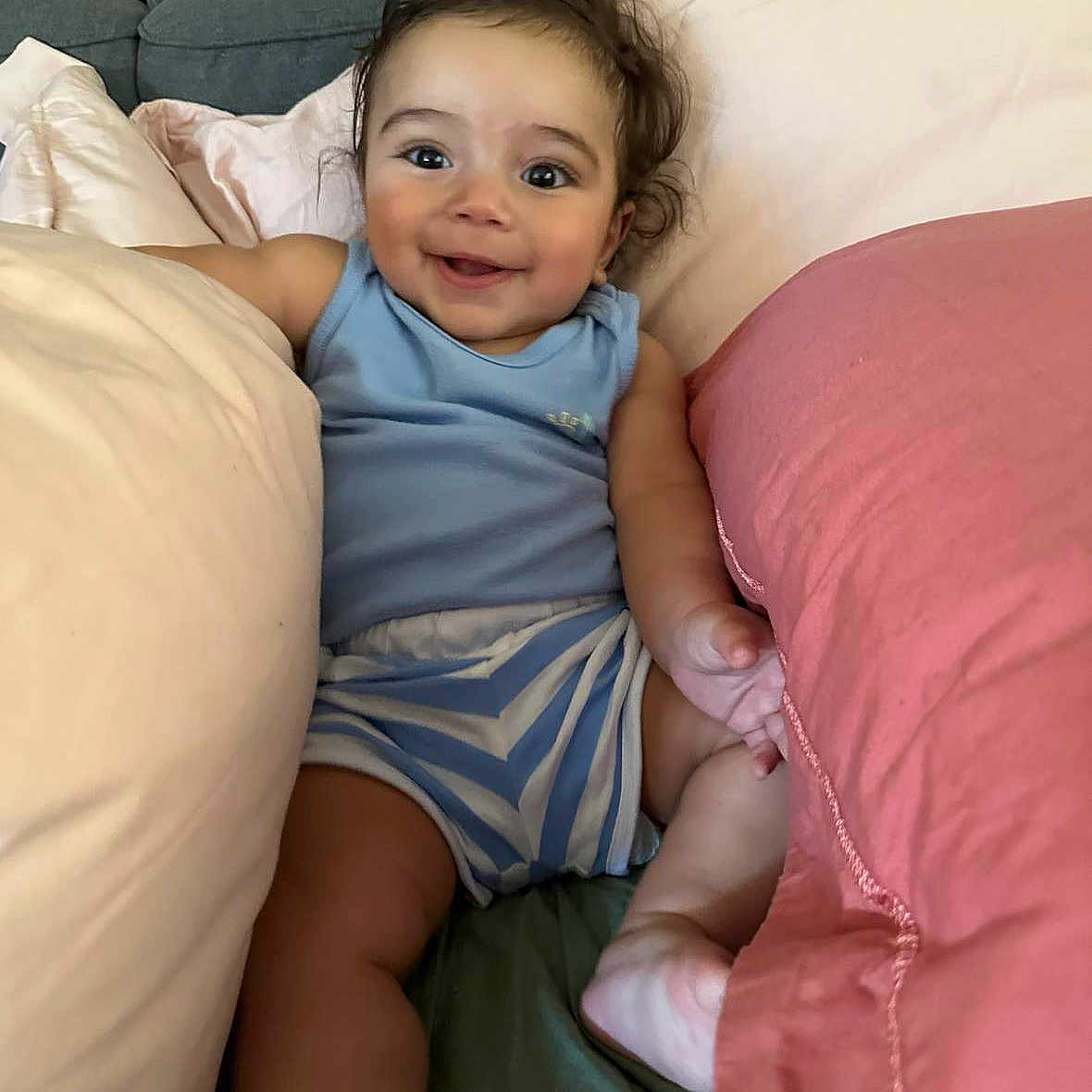 Ahmed a rejoint le concours — aidez-le/la à gagner de superbes lots ! baby, blue_clothing, child, comfort, couch, cute, face, hair, happy, indoors, infant, living_room, person, pillows, relaxed, seated, skin, smiling, soft, striped_shorts