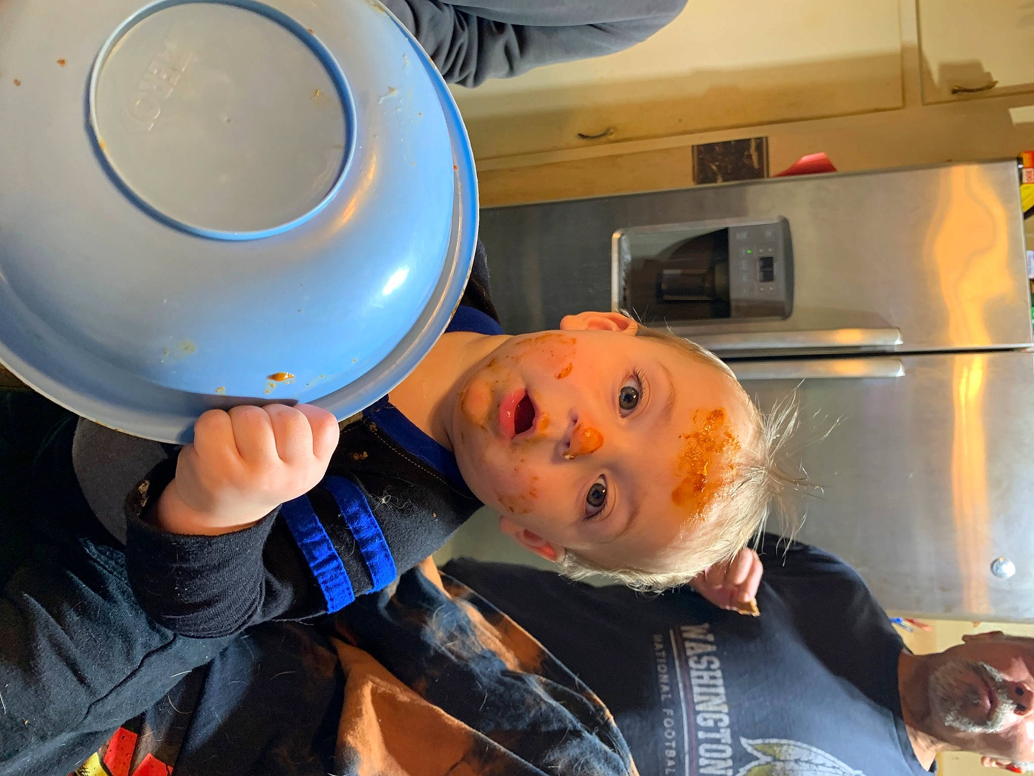 Bentley is registered to the contest to win money with this photo: cabinetry, chair, child, circle, cooking, electric_blue, fun, gas, helmet, home_appliance, homemaker, kitchen, kitchen_appliance, machine, major_appliance, orange, person, personal_protective_equipment, refrigerator, room