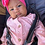 baby, headband, pink_clothing, child, infant, harness, seatbelt, face, portrait, closeup, cute, soft_fabric, buttoned_clothing, indoor, black_straps, expression, person, small_flower_pattern, skin, young_child