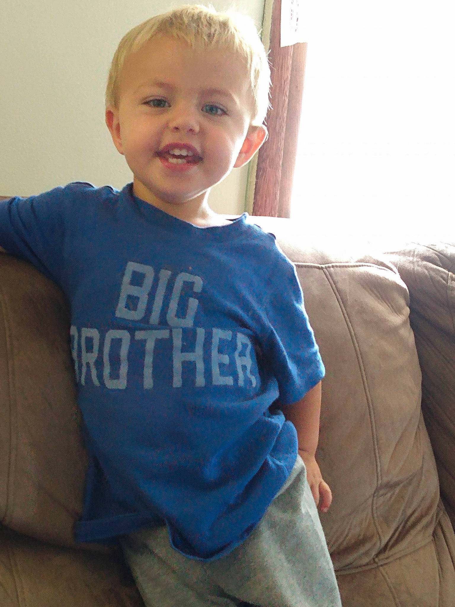 Caspian is registered to the contest to win money with this photo: arm, baby, baby_toddler_clothing, blond, blue, cheek, child, eye, face, facial_expression, happy, head, person, shoulder, sitting, skin, sleeve, smile, standing, t_shirt