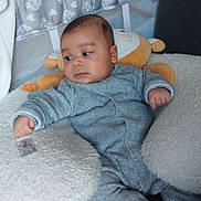 Raphaël participe au concours pour gagner de l'argent avec cette photo : baby, blanket, child, comfort, cushion, cute, face, footwear, furniture, grey_clothing, hand, indoors, infant, living_room, onesie, plush_toy, portrait, resting, seated, soft_fabric