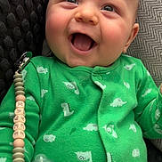 Kayce joined the competition — help win amazing prizes! baby, child, green_onesie, dinosaur_print, pacifier, smiling, happy, infant, cute, clothing, face, hand, indoor, portrait, young_child, comfort, texture, closeup, joy, baby_accessory