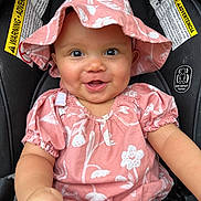 Lily is registered to the contest to win money with this photo: baby, infant, smiling, pink_hat, pink_clothing, car_seat, child, cute, happy, face, headwear, sitting, apparel, young_child, portrait, warning_labels, indoors, skin, one_person, closeup