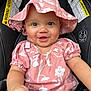 baby, infant, smiling, pink_hat, pink_clothing, car_seat, child, cute, happy, face, headwear, sitting, apparel, young_child, portrait, warning_labels, indoors, skin, one_person, closeup