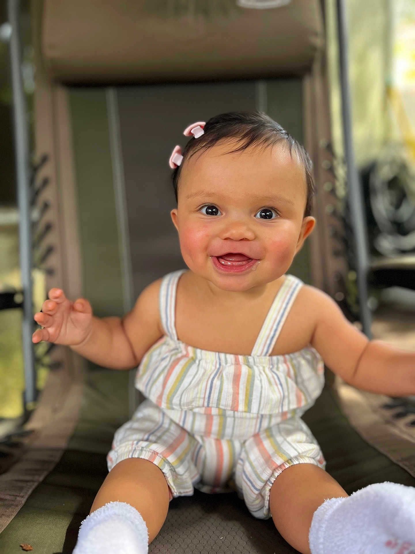 Lily joined the competition — help win amazing prizes! baby, child, smiling, happy, sitting, romper, striped_clothing, socks, chair, cushion, indoor, face, person, cute, infant, hair_clip, portrait, skin, expression, young