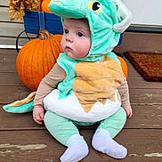 Ethan. is registered to the contest to win money with this photo: baby, child, costume, dinosaur_costume, pumpkin, autumn, fall, leaves, porch, wooden_floor, cute, plush, sitting, outdoor, seasonal, holiday, face, clothing, sock, expression