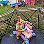 toddler, toy, unicorn, trampoline, outdoor, grass, playground, basketball, tricycle, slide, child, happy, smiling, barefoot, green_tshirt, plastic_toy, fence, summer, fun, play