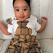 Raelynn joined the competition — help win amazing prizes! baby, child, infant, headband, plaid, outfit, bear_applique, white_chair, quilted_chair, cute, smiling, sitting, indoors, person, portrait, clothing, fashion, expression, baby_fashion, young_child