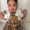 baby, child, infant, headband, plaid, outfit, bear_applique, white_chair, quilted_chair, cute, smiling, sitting, indoors, person, portrait, clothing, fashion, expression, baby_fashion, young_child