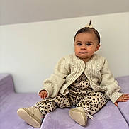 Rose Percebois a rejoint le concours — aidez-le/la à gagner de superbes lots ! toddler, child, baby, sitting, couch, purple_couch, knitted_sweater, leopard_print, footwear, indoor, cute, portrait, person, small_pony_tail, clothing, furniture, expression, home, soft_lighting, casual
