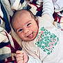 baby, infant, smiling, tongue_out, blanket, colorful, clothing, cute, happy, portrait, child, young, face, hand, fist, soft, warm, lying_down, cozy, expression
