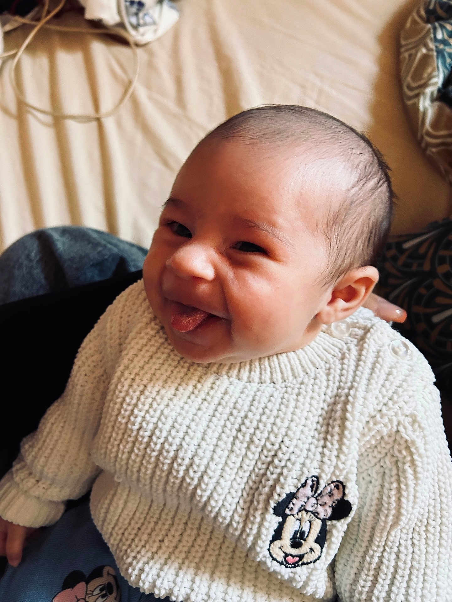 Rose a rejoint le concours — aidez-le/la à gagner de superbes lots ! baby, child, face, smile, tongue_out, knit_sweater, white_clothing, minnie_mouse, patch, indoor, person, cute, happy, infant, portrait, seated, hand, skin, head, young