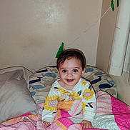 Jessamine joined the competition — help win amazing prizes! baby, child, smiling, bed, blanket, quilt, pillow, onesie, sunflower, indoor, wall, wire, tape, curly_hair, happy, person, cute, colorful, cozy, portrait