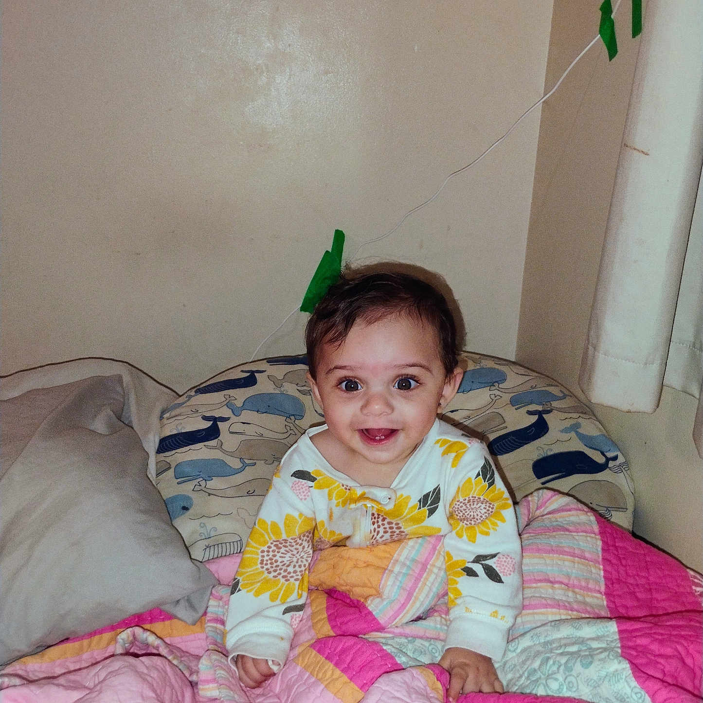Jessamine joined the competition — help win amazing prizes! baby, child, smiling, bed, blanket, quilt, pillow, onesie, sunflower, indoor, wall, wire, tape, curly_hair, happy, person, cute, colorful, cozy, portrait