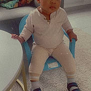 Aaron participe au concours pour gagner de l'argent avec cette photo : child, toddler, indoor, chair, blue_chair, table, carpet, couch, pillow, clothing, socks, sandals, face, person, furniture, living_room, curious, seated, expression, home