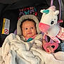 Journi is registered to the contest to win money with this photo: baby, blanket, car_seat, child, colorful, comfort, curious, cute, face, hand, indoor, infant, pattern, pink, plush_toy, portrait, seat, soft_toy, unicorn, white