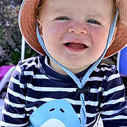 Louis a rejoint le concours — aidez-le/la à gagner de superbes lots ! toddler, child, smiling, hat, striped_shirt, shark_graphic, outdoor, sunlight, blue_eyes, happy, cute, baby, face, clothing, summer, playful, portrait, fun, person, headwear