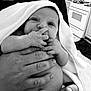 Aurora is registered to the contest to win money with this photo: baby, newborn, infant, towel, hand, fingers, umbilical_stump, black_and_white, person, kitchen, stove, adult_hand, diaper, curious, wrapped, holding, indoor, expression, portrait, cute