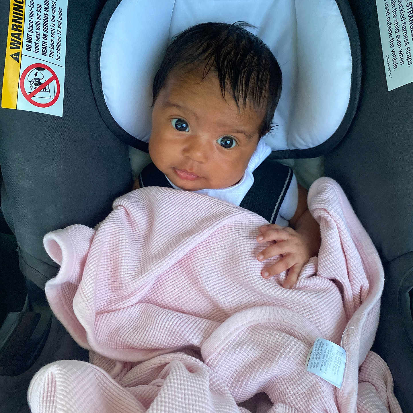 Alena is registered to the contest to win money with this photo: baby, blanket, car_seat, child, clothing, cute, expression, face, hair, hand, indoors, infant, looking, pink, portrait, safety, seatbelt, soft, wrapped, young