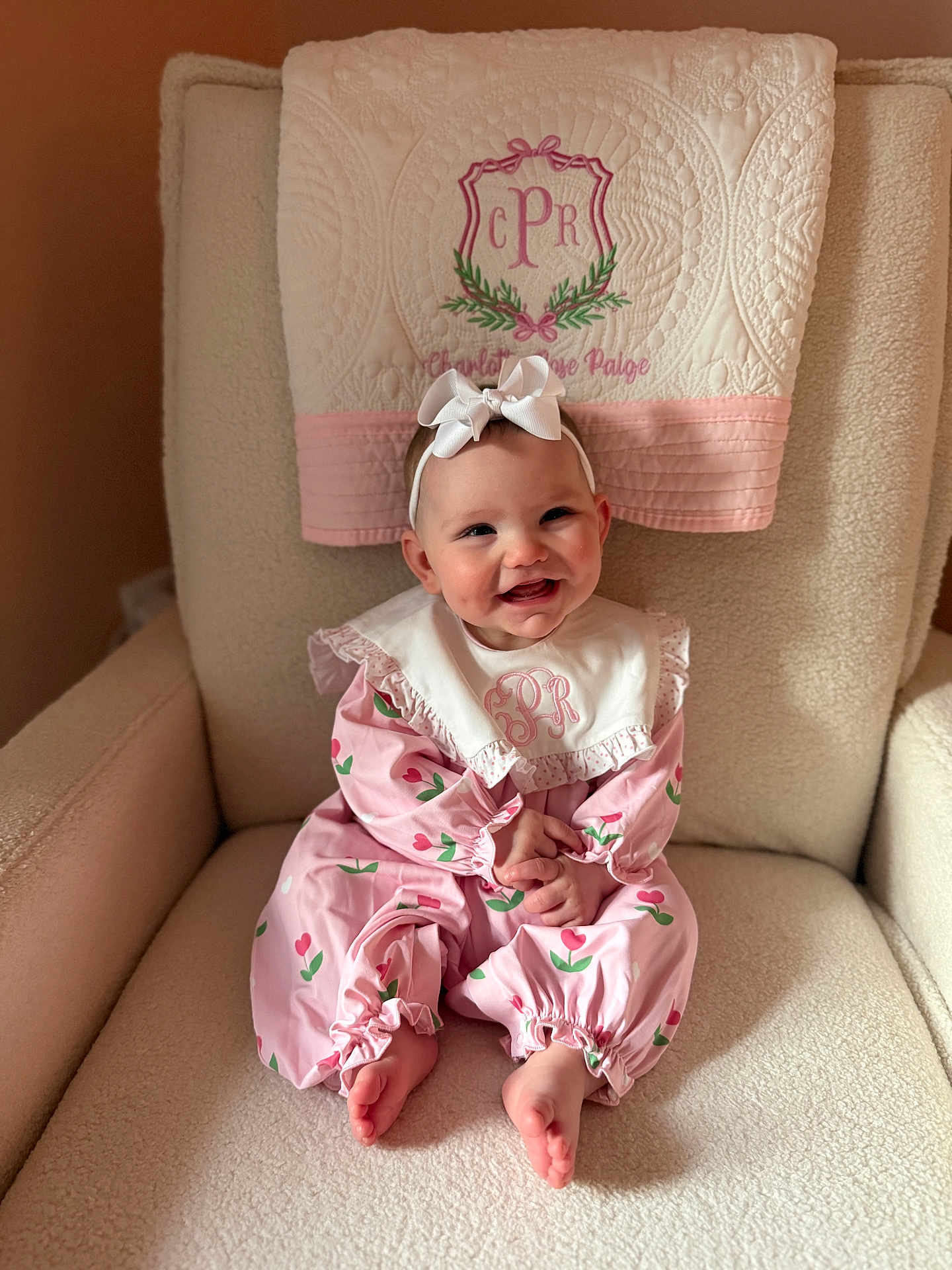 Charlotte joined the competition — help win amazing prizes! baby, infant, headband, bow, pink_outfit, tulip_pattern, quilted_towel, armchair, nursery_chair, smile, rosy_cheeks, sitting, bare_feet, hands_clasped, portrait, soft_texture, embroidered_monogram, pink_color_palette, cozy, adorable