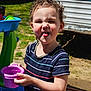 cheeky, child, curly_hair, daytime, earrings, expression, fun, grass, outdoor, person, playful, playset, purple_cup, smile, striped_shirt, summer, sunlight, tongue_out, toy, young_child