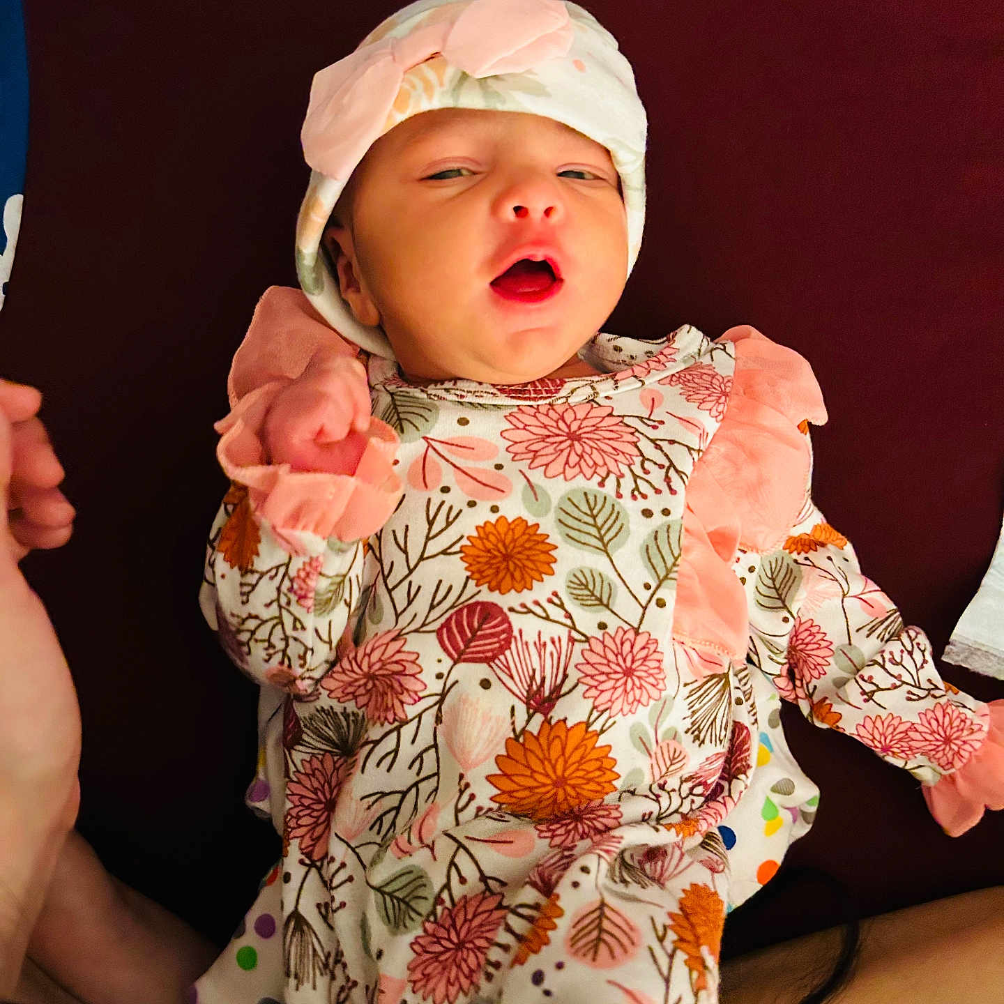 Mirha joined the competition — help win amazing prizes! baby, background, bow, child, clothing, cute, expression, face, floral_pattern, hand, hat, infant, lying_down, newborn, orange, person, pink, soft, warm, white