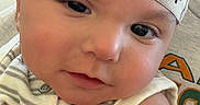 Kylan joined the competition — help win amazing prizes! adult_hand, arm, baby, casual, cheeks, child, closeup, cute, expression, eyes, face, hand, headband, indoors, infant, light, person, portrait, skin, striped_clothing