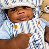 baby, infant, child, portrait, close_up, face, eyes, hat, striped_clothing, overalls, blue, white, sitting, lying_down, teddy_bear, stuffed_animal, blanket, indoors, smiling, adorable