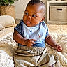 Zahli-Emyr is registered to the contest to win money with this photo: baby, infant, child, portrait, sitting, smiling, face, eyes, blue_shirt, bib, beige_clothing, skirt, socks, blanket, bedroom, nursery, teddy_bear, houseplant, indoors, cozy