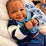 baby, infant, child, smiling, portrait, indoor, blanket, bib, teddy_bear, toy, sitting, lying_down, clothing, blue, happy, face, hands, nursery, cozy, photography