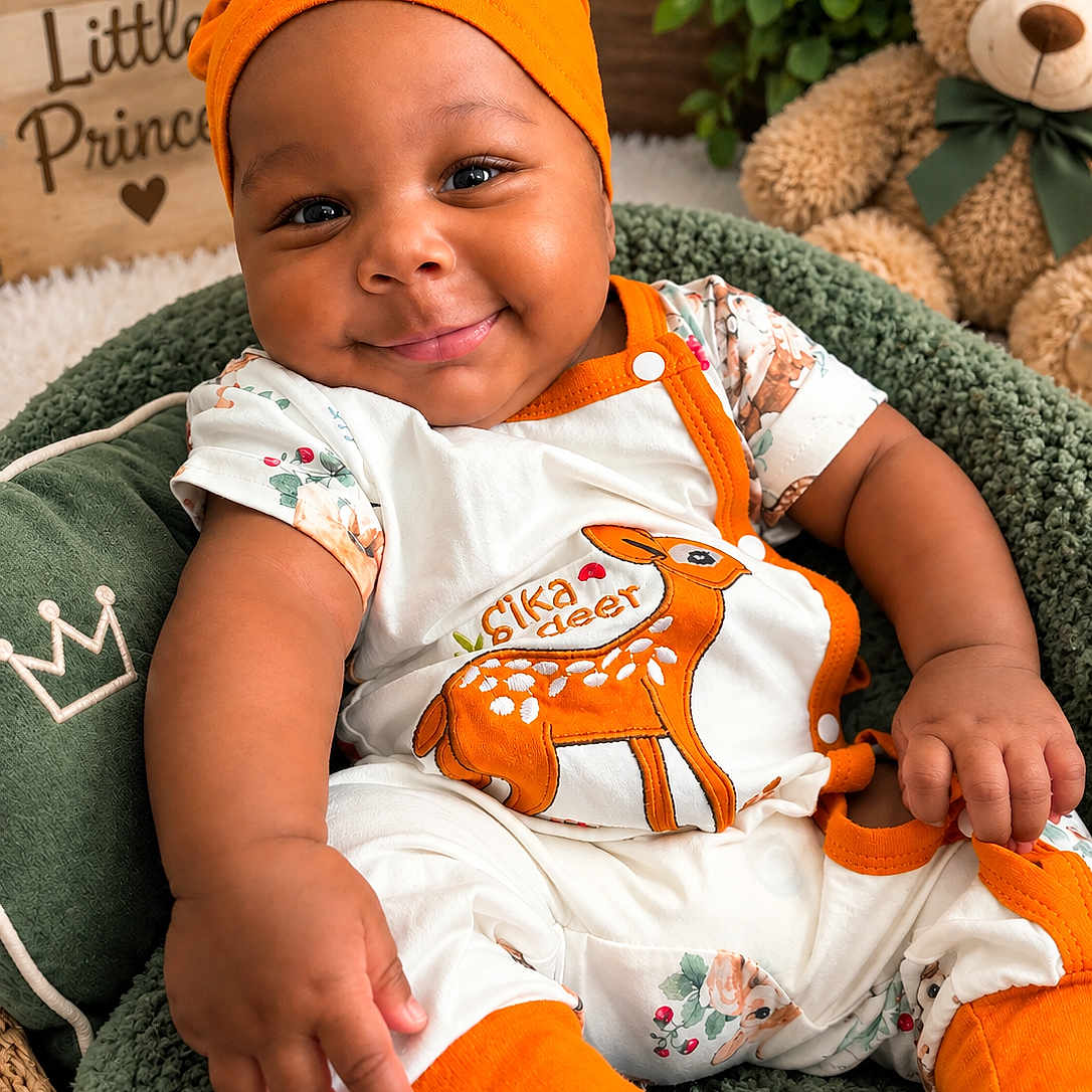 Zahli-Emyr joined the competition — help win amazing prizes! baby, infant, child, smiling, portrait, sitting, indoors, orange_hat, onesie, deer_pattern, teddy_bear, stuffed_animal, green_blanket, cozy, nursery, cushion, plants, decor, crown_sign, happy