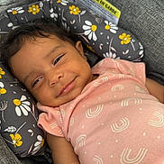 Aaliyah joined the competition — help win amazing prizes! apparel, baby, child, closeup, cushion, cute, face, floral_pattern, happy, head_support, indoors, infant, person, pink_clothing, portrait, relaxing, seat, skin, smiling, soft_fabric