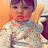 baby, child, pajamas, head_wrap, floral_pattern, indoor, pillow, seated, cute, portrait, face, expression, clothing, soft_lighting, home, young_child, person, infant, headwear, sitting