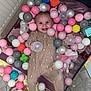 baby, baby_girl, cheerful, child, colorful, cute, face, fun, happy, indoor, infant, lying_down, mesh_sides, pajamas, plastic_balls, play_area, playpen, smiling, soft_toys, toys
