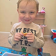 Jason is registered to the contest to win money with this photo: child, smiling, cookie, toy, table, indoor, playroom, young_child, face, clothing, furniture, background, toy_kitchen, plate, hand, person, blue, red, beige, carpet