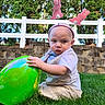 Jason is registered to the contest to win money with this photo: child, toddler, grass, balloon, outdoor, bunny_ears, headband, white_fence, trees, daylight, green_balloon, baby, cute, serious_face, nature, playtime, summer, casual_clothing, headwear, fun