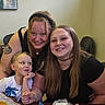 black_shirt, bracelet, chair, child, drink, face, family, food, friendship, happy, headband, indoor, long_hair, necklace, portrait, smile, table, tattoo, white_shirt, woman