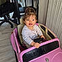 Iris a rejoint le concours — aidez-le/la à gagner de superbes lots ! child, toddler, toy_car, pink_car, steering_wheel, smile, pony_tail, seat, indoor, radiator, floor, desk, office_chair, shoes, wires, reflection, mirror, casual_clothing, playtime, cute
