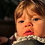 child, toddler, baby, face, eyes, lips, hair, close_up, portrait, sunlight, ruffled_collar, seatbelt, cheek, skin, mouth, expression, indoor, blurred_background, warm_lighting, curious
