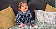 Iris a rejoint le concours — aidez-le/la à gagner de superbes lots ! baby, blanket, child, couch, curious, cushions, cute, face, floral_pattern, hair_clip, indoor, looking_up, pillow, plush_blanket, portrait, shoe, sitting, sofa, striped_shirt, toddler