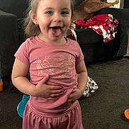 Journey joined the competition — help win amazing prizes! toddler, child, pink_clothing, shorts, tshirt, smiling, tongue_out, living_room, carpet, couch, dog, blanket, toy, earrings, person, happy, indoor, hair_tied, home, cute