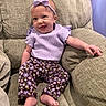 Lyla joined the competition — help win amazing prizes! armchair, baby, barefoot, bow, child, clothing, couch, face, floral_pants, furniture, happy, headband, home, indoor, infant, lavender, photography, portrait, sitting, smiling