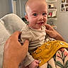 Lyla joined the competition — help win amazing prizes! baby, infant, smile, hands, blanket, striped_clothing, yellow_blanket, animal_print, indoor, home, person, cute, young_child, holding, face, happy, portrait, sitting, cozy, warm_lighting
