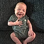 baby, infant, smiling, happy, sitting, couch, clothing, onesie, face, head, skin, hand, foot, leg, indoors, child, person, cute, joy, expression