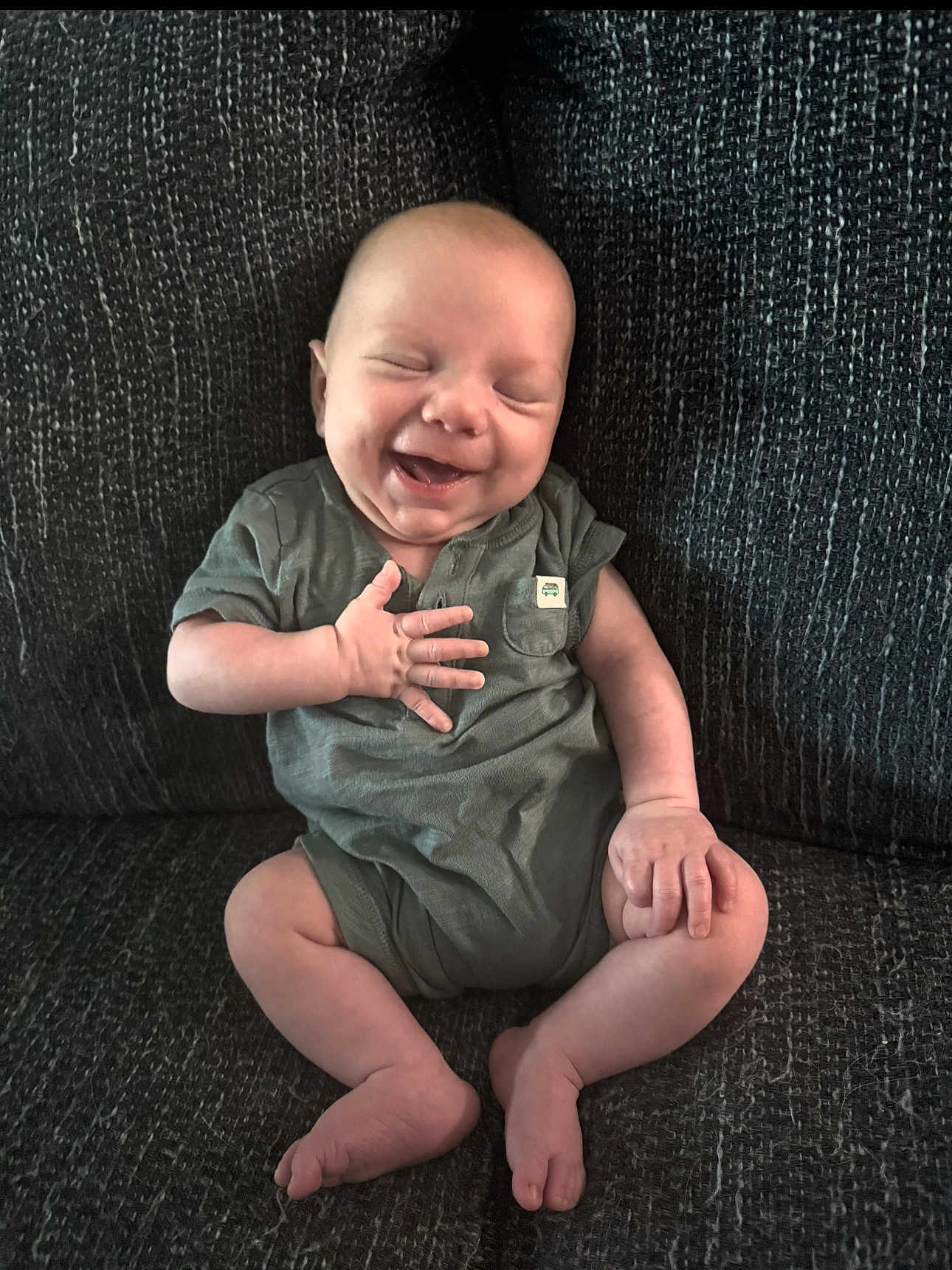 Grayson is registered to the contest to win money with this photo: baby, infant, smiling, happy, sitting, couch, clothing, onesie, face, head, skin, hand, foot, leg, indoors, child, person, cute, joy, expression