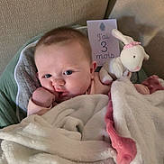 Soëlya a rejoint le concours — aidez-le/la à gagner de superbes lots ! baby, infant, newborn, blanket, plush_bunny, milestone_card, french_text, couch, pillow, cozy, swaddle, portrait, cheeks, eyes, hand, thumb, soft_texture, pink, toy, security_blanket