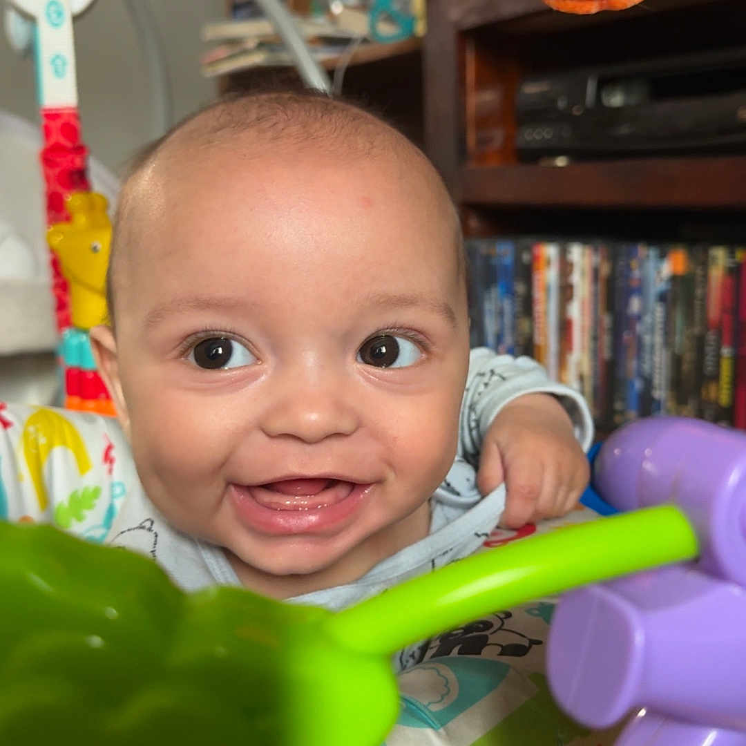 Credence is registered to the contest to win money with this photo: baby, background, bright, child, closeup, colorful, cute, expression, face, focus, furniture, happy, indoor, infant, joy, person, playtime, shelf, smiling, toy