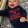 baby, infant, smiling, onesie, clothing, text_on_clothing, bed, blanket, pattern, happy, cute, child, face, mouth_open, hand, lying_down, indoor, person, young_child, expression