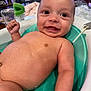baby, infant, smile, bath, water, tub, skin, face, eyes, hand, arm, indoor, plant, blurred_background, happy, cute, child, person, bath_time, closeup